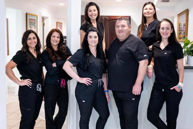 The Campo Dentistry team — six members of staff in matching black scrubs, photographed in the office hallway